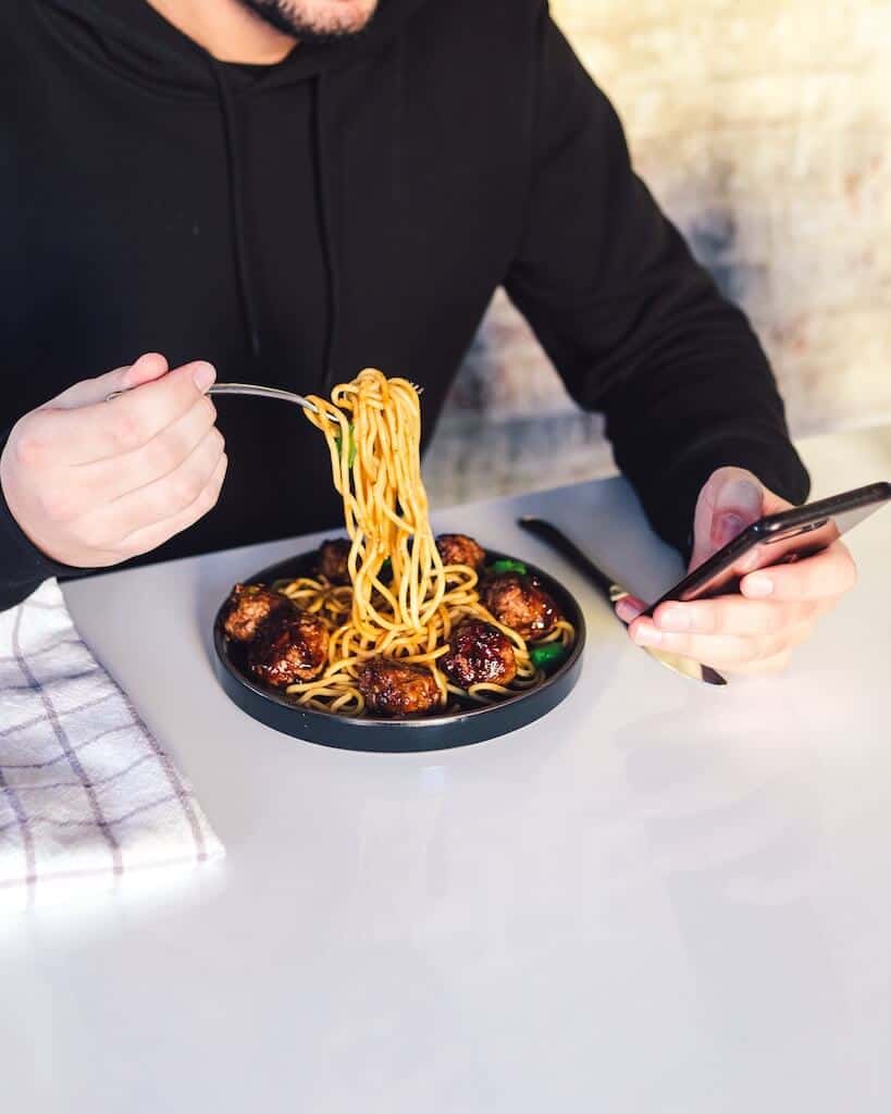 Man eating dinner while looking at his phone 