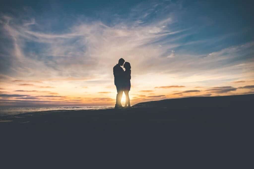 couple standing in front of a summer sunset 