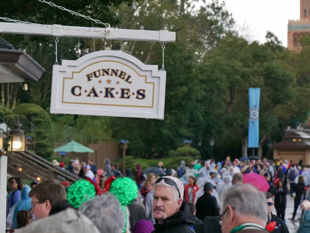 Crowd of people at Disney World with sign that says Funnel Cakes