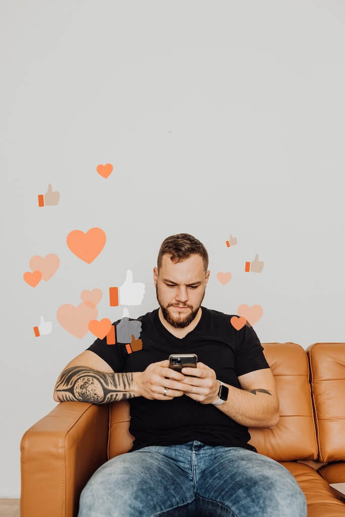 Man sitting on couch, texting. hearts and likes floating above him.