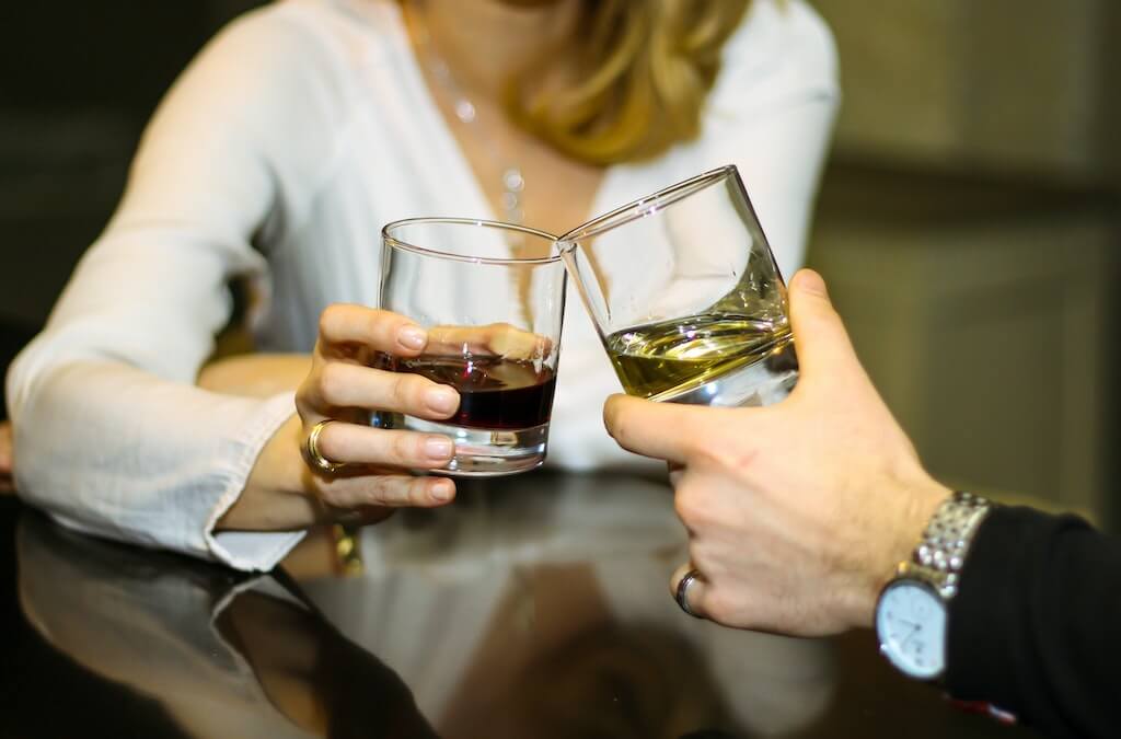 hands of couple clinking glasses filled with wine.