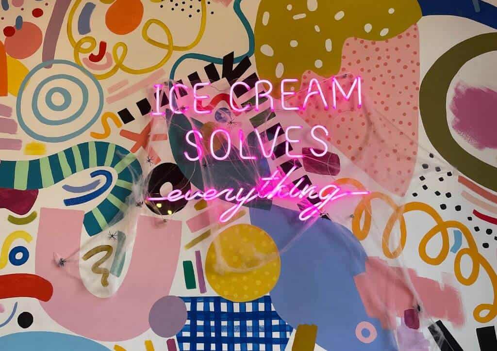 colorful wall with neon lights saying "ice cream solves everything".