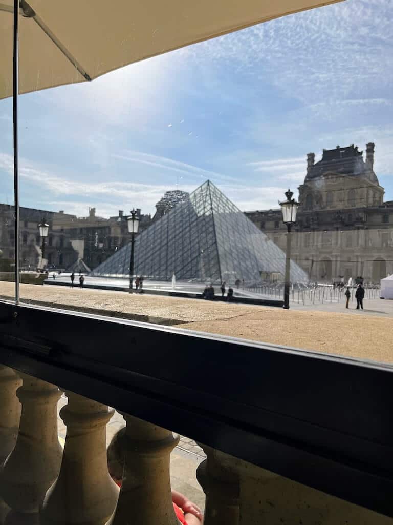 a shot of the Louvre glass pyramid from a cafe. 