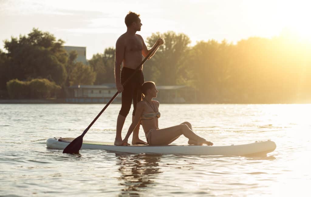 man and woman on vacation on stand up paddle boards.