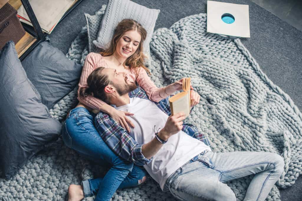 image shows a couple hugging and reading together in bed.