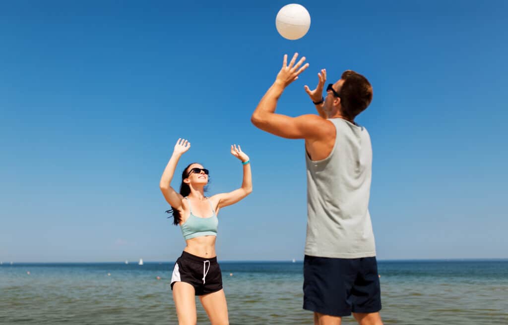 a couple playing volleyball on the beach.