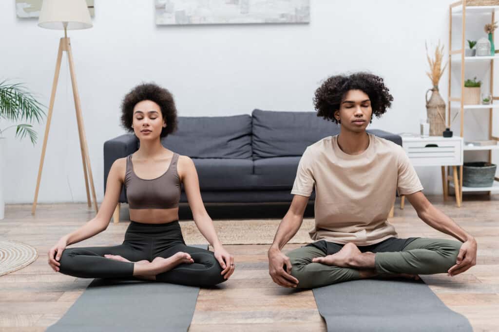 image shows couple doing yoga in their living room. 