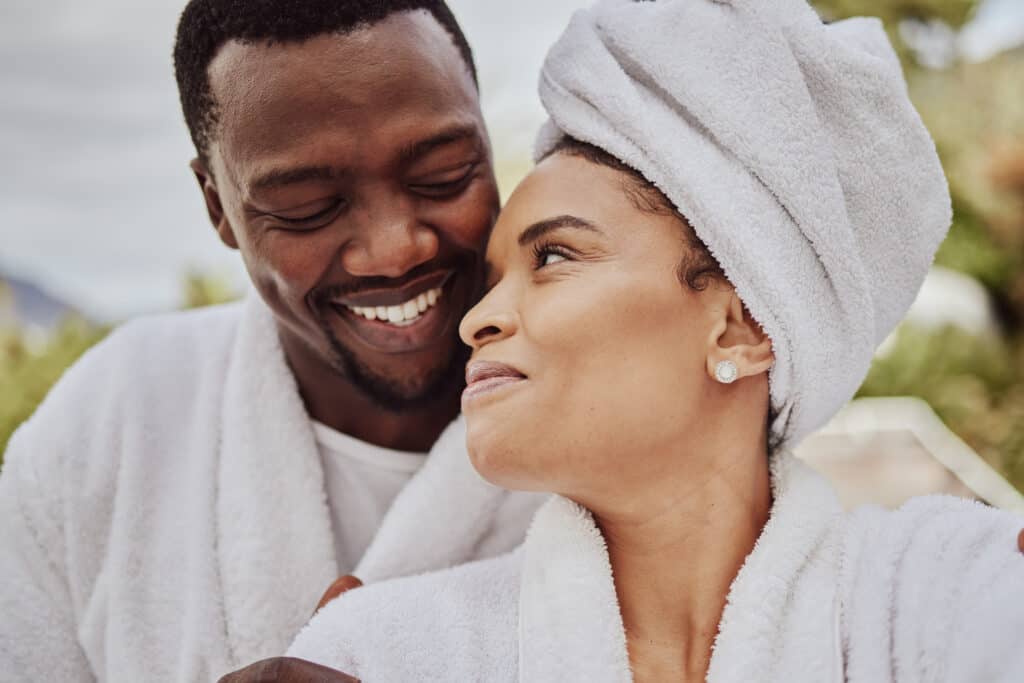 couple smiling at each other while in bathrobes and towels after the spa. 